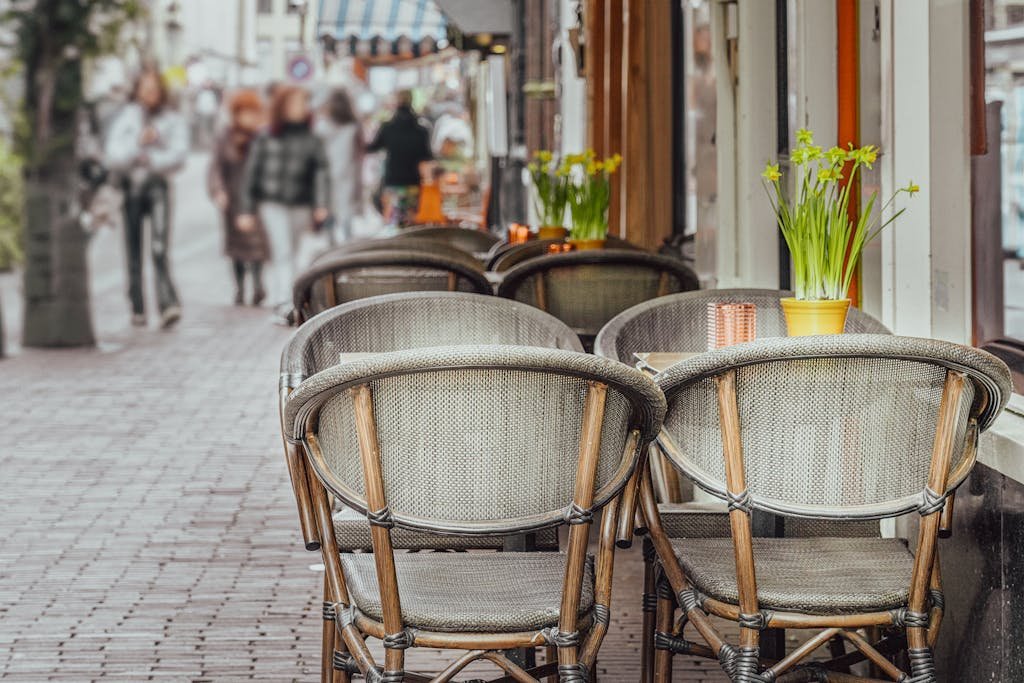 Your Complete Dutch Food Guide: What to Eat in Amsterdam and Beyond 13 Cozy street café in Amsterdam with outdoor seating, daffodils, and blurred pedestrians.
