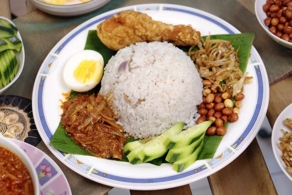 Delicious Nasi Lemak served with fried chicken, sambal, peanuts, and boiled egg.