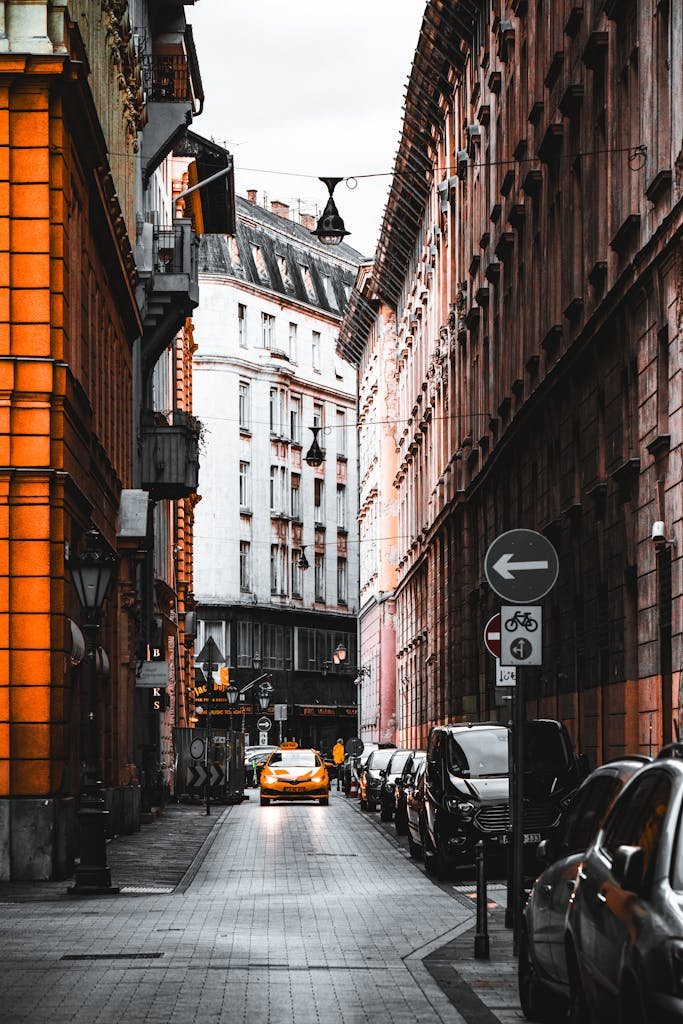 20 Best Things to Do in Budapest, Hungary: An In-depth Travel Guide 16 Dramatic view of a narrow Budapest street with vibrant architecture and a striking yellow car.