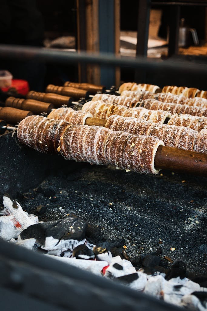 20 Best Things to Do in Budapest, Hungary: An In-depth Travel Guide 10 Freshly baked chimney cakes cooking over hot coals, capturing the essence of rustic food preparation.