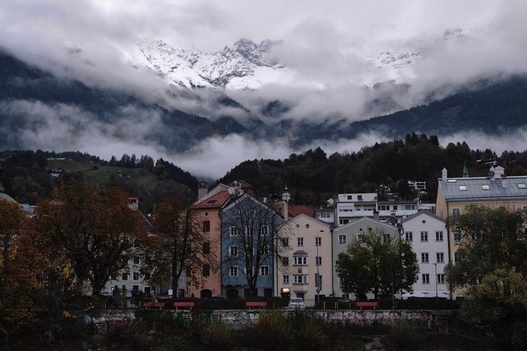5 Days in Austria: The Perfect Austria Road Trip Itinerary 17 Picturesque Innsbruck buildings under snow-capped mountains and misty sky.