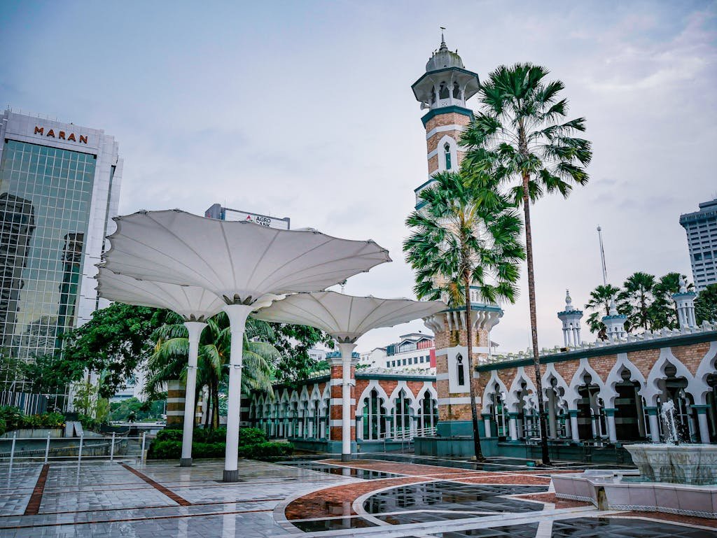 View of Jamek Mosque with lush palm trees and modern architectural elements in Kuala Lumpur, Malaysia during my travel in Malaysia