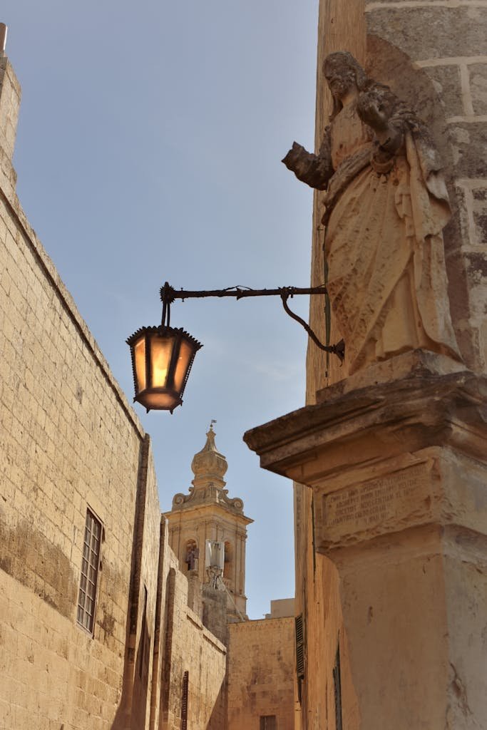 21 Best things to do in Mdina, Malta's Silent City 3 A beautiful historic street in Mdina, Malta, showcasing a traditional lantern and intricate sculpture in mdina a malta