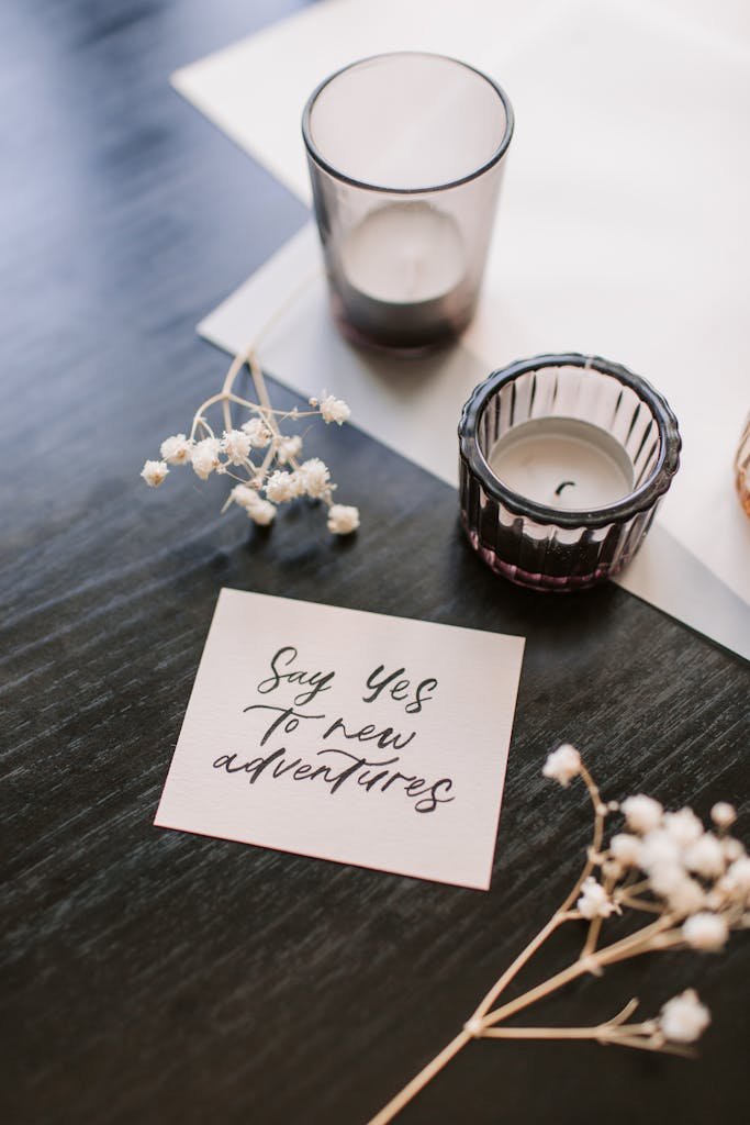 A motivational note with candles and flowers arranged on a dark wooden surface.