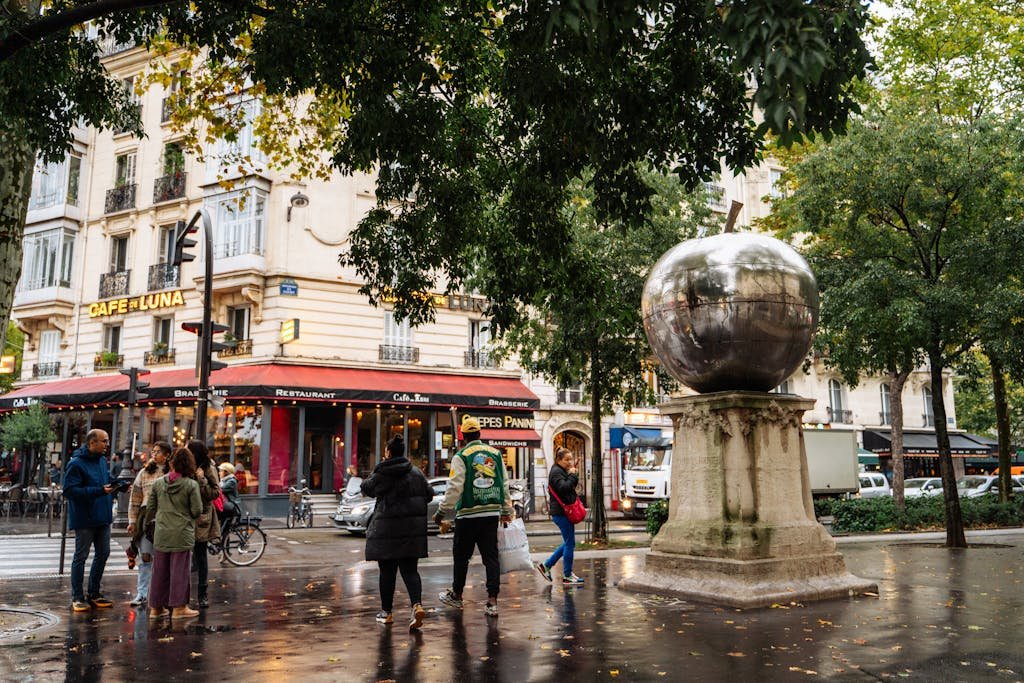 11 Ways For Getting Around Paris Efficiently: Ultimate guide 10 A vibrant Paris street scene featuring a cafe, sculpture, and people.