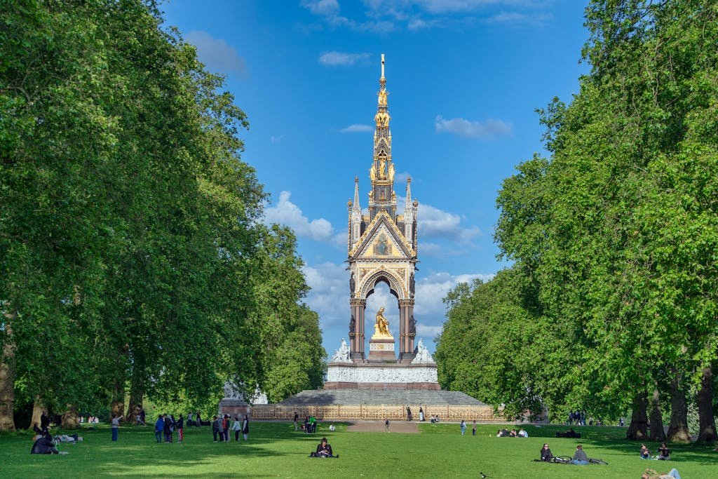 Albert Memorial surrounded by lush trees in Hyde Park, London, under a clear blue sky.