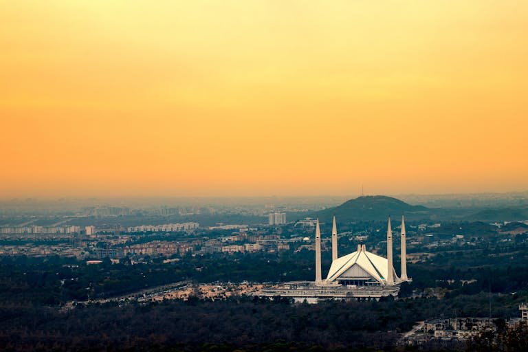 Captured from above, Islamabad's Faisal Mosque silhouetted against a vibrant sunset sky.