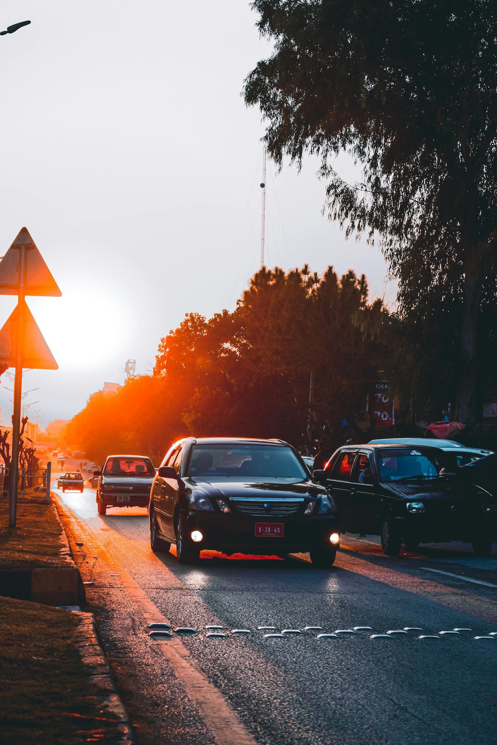 Cars driving on a road during sunset in Islamabad, creating a warm, vibrant scene.