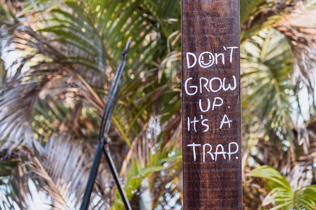 Close-up of an inspiring quote on a wooden pole amidst lush palm leaves.