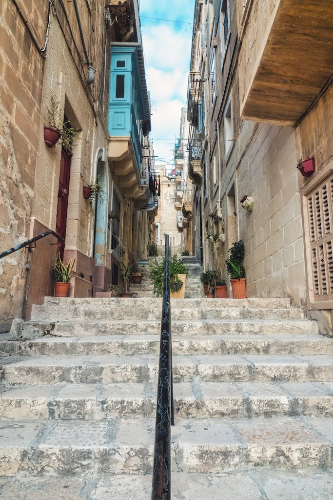 Explore a quaint stone staircase amid historic Maltese architecture, perfect for travel inspiration.