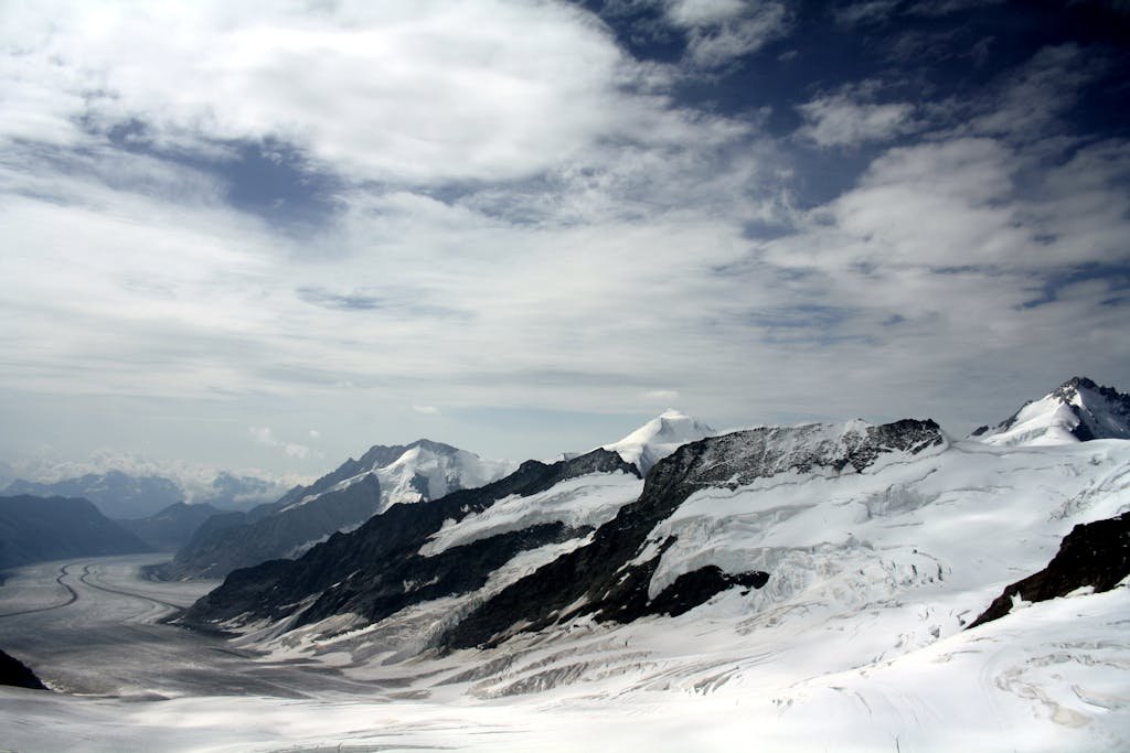 Majestic view of snowy alpine mountains and glaciers under dramatic sky.