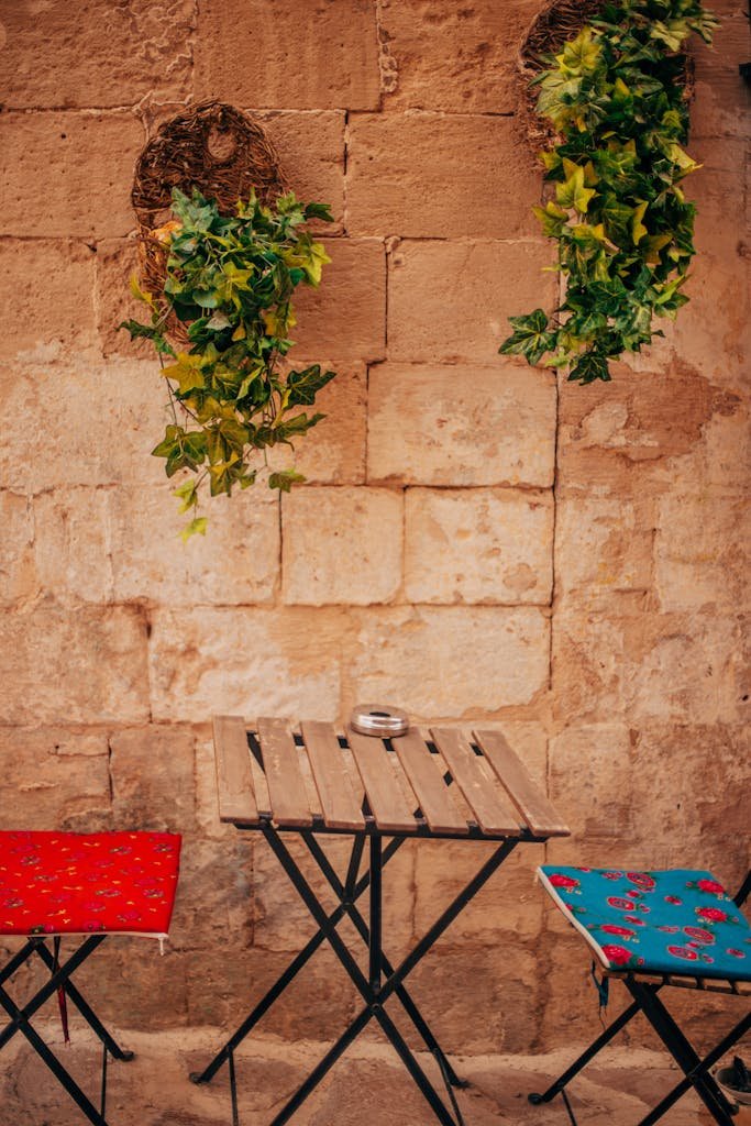 21 Best things to do in Mdina, Malta's Silent City 11 Quaint sidewalk cafe with wooden tables and potted plants against a stone wall in Mdina a Malta