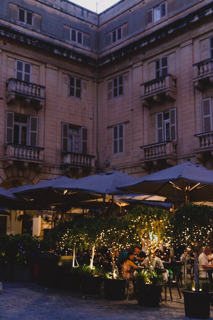 Romantic evening dining under twinkling lights in a historic courtyard.
