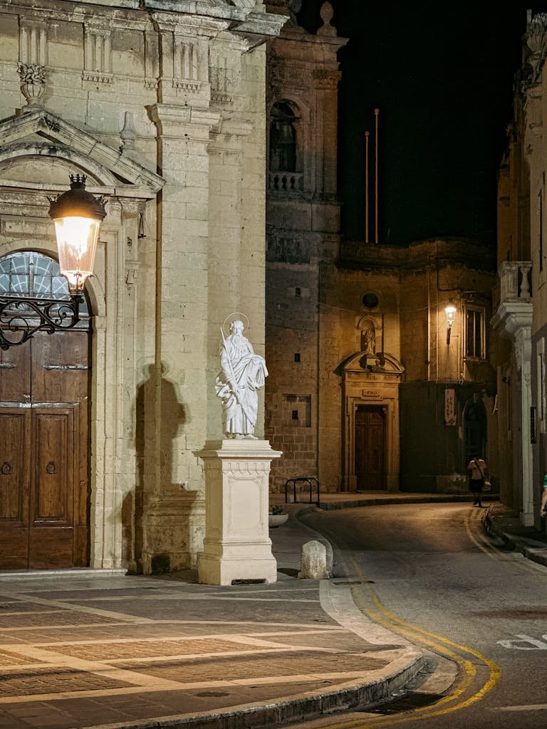 21 Best things to do in Mdina, Malta's Silent City 8 Serene night view of a historic street in Mdina a Malta featuring a prominent statue and warm lighting.