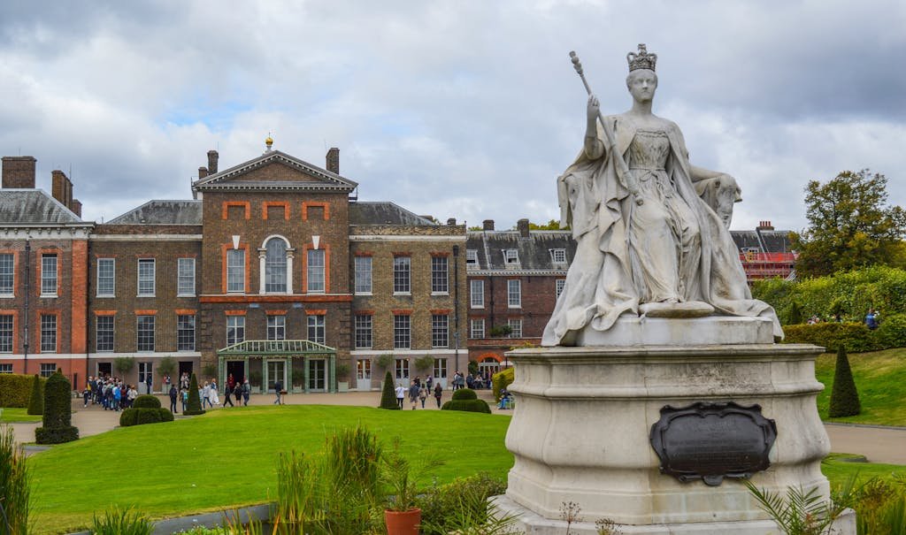 Statue of Queen Victoria located in front of Kensington Palace in London under cloudy sky