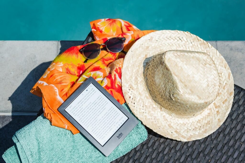 Kindle, hat and bath towel placed on beech