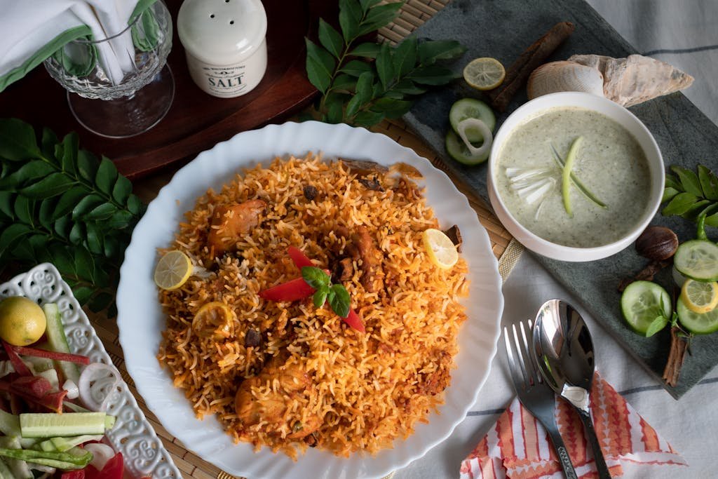 Top view of traditional Pakistani biryani, raita, and salad, beautifully arranged on a table.