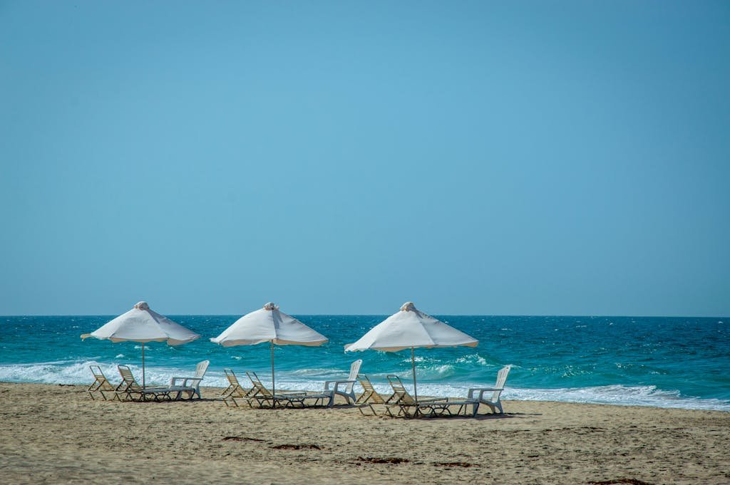 Tranquil beach scene with sunloungers and parasols by blue ocean waves.
