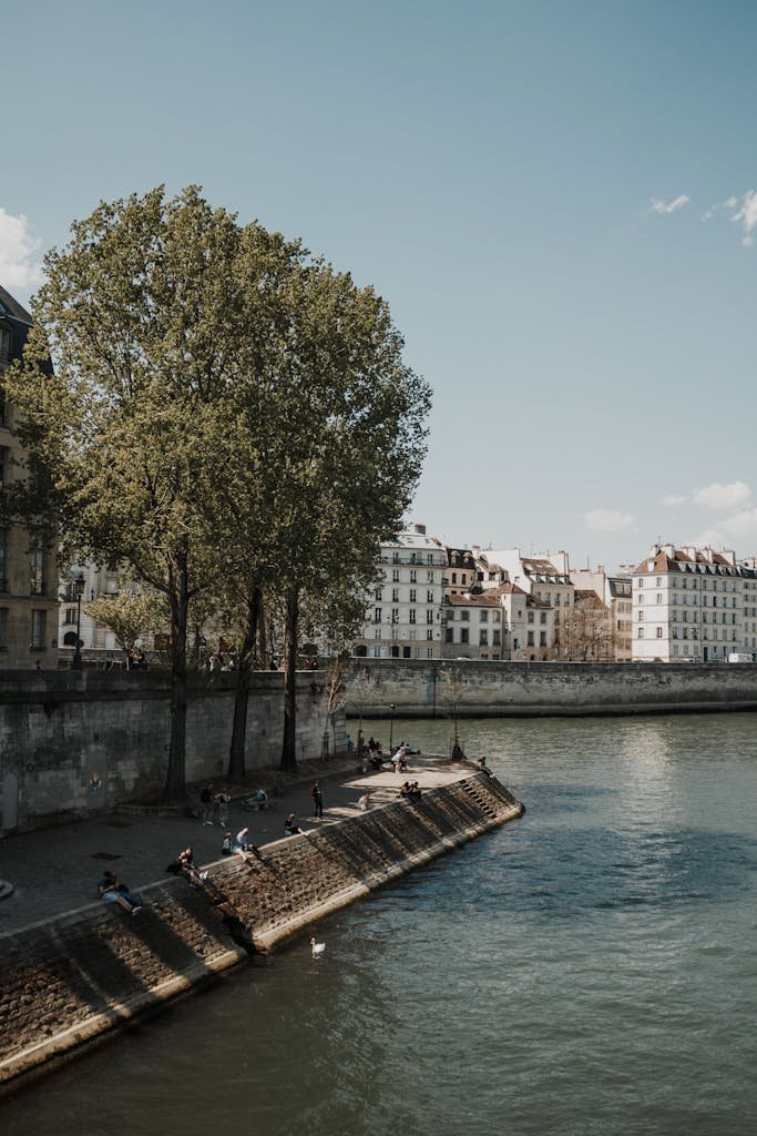 41 best Things to Do in Paris: Iconic Sights to Hidden Gems 28 Tranquil riverside scene in Paris with people relaxing by the Seine on a sunny day.
