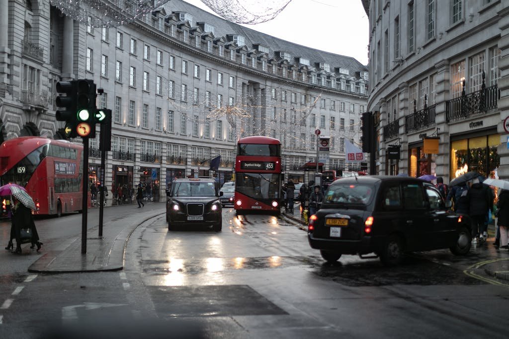 Urban scene of London featuring double decker buses, taxis, and pedestrians in Piccadilly Circus.