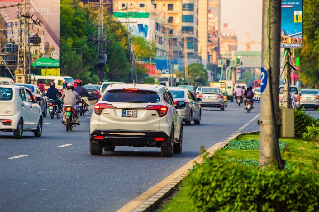 Urban street scene in Punjab, Pakistan, bustling with traffic including cars and motorcycles.