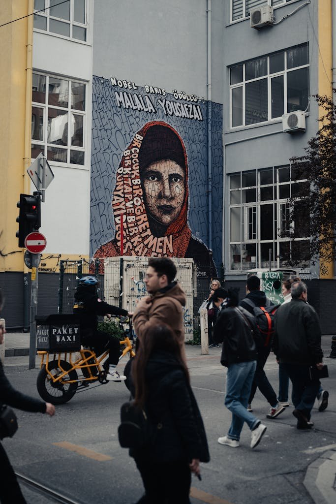 Vibrant street scene in İstanbul featuring a colorful mural of Malala Yousafzai promoting peace and activism.