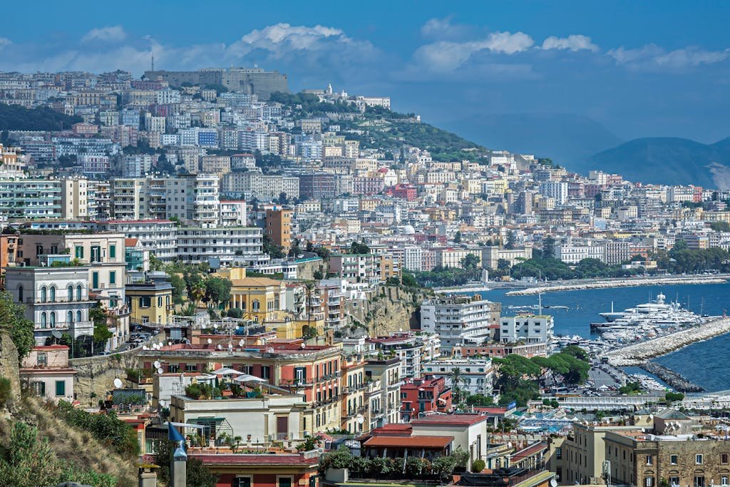 A breathtaking view of the colorful buildings and coastline of Naples, Italy, showcasing the vibrant city life and stunning sea.