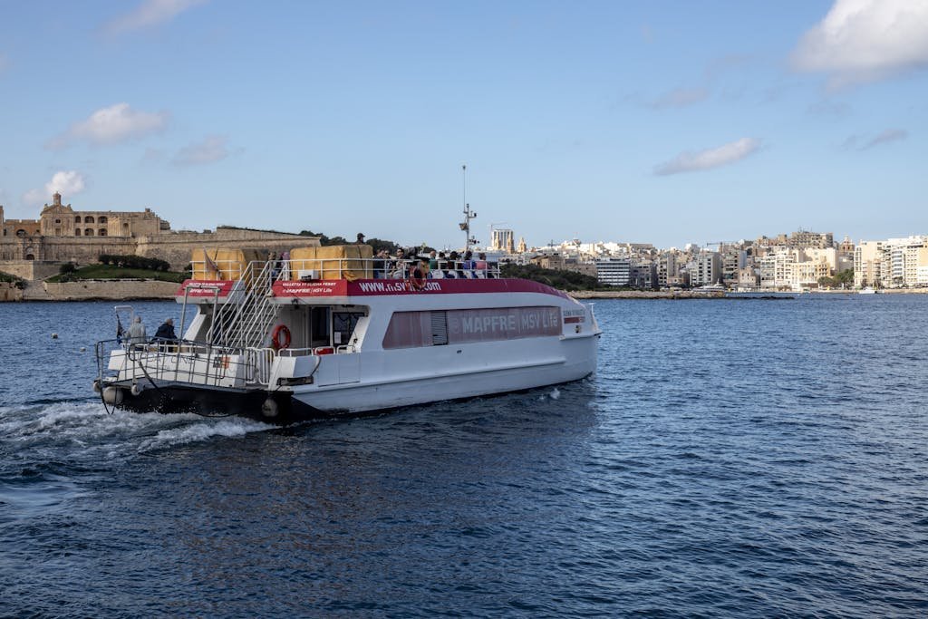 Is Malta Expensive? My Malta Budget Breakdown 2026 8 A passenger ferry cruising along a cityscape river scene in daylight.