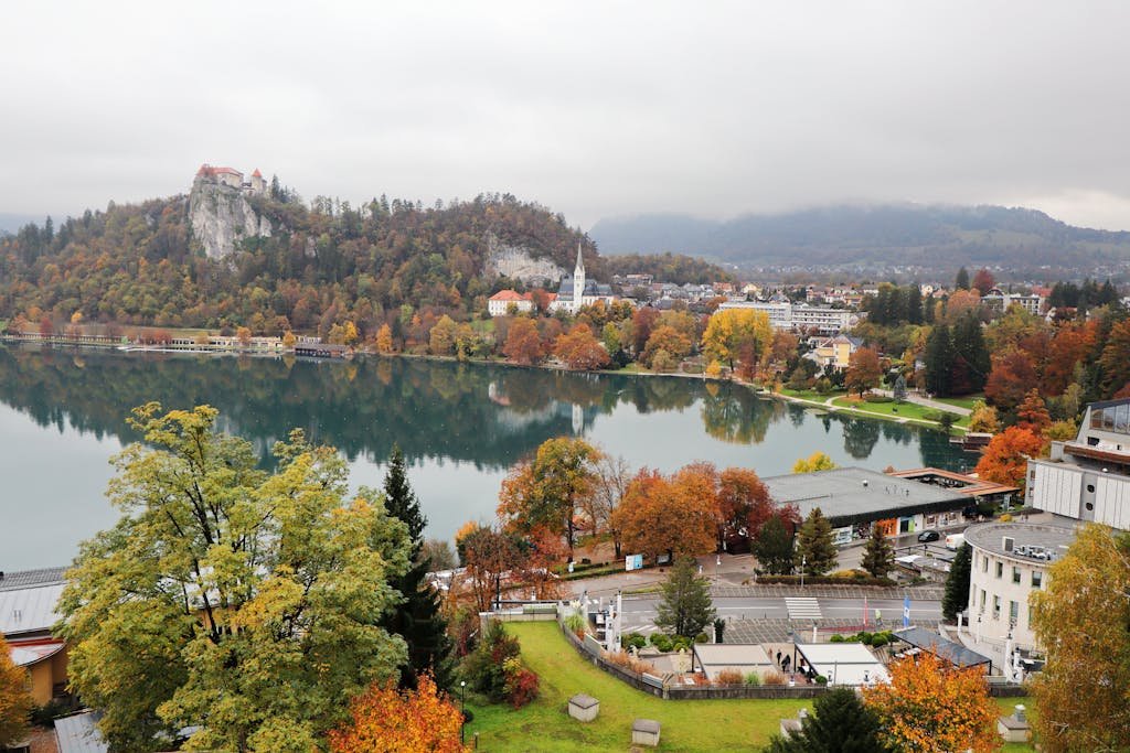 A serene aerial view of Lake Bled in Slovenia, showcasing vibrant autumn colors and the picturesque town of Bled.