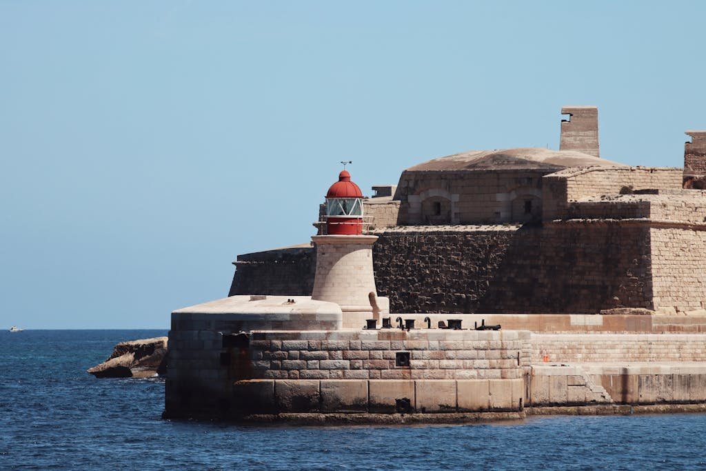 Is Malta Expensive? My Malta Budget Breakdown 2026 11 A striking lighthouse stands by ancient fortifications on the seaside at Valletta, Malta.