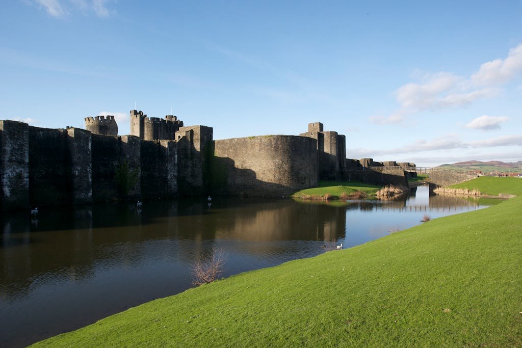 A stunning view of the historic Caerphilly Castle in Wales, reflected in a calm river.