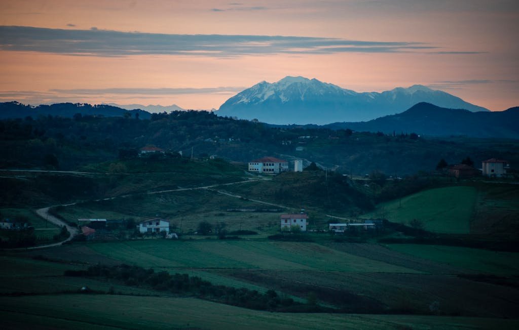 A tranquil rural scene in Albania, showcasing rolling hills and mountains under a sunset sky one of the underrated countries in europe