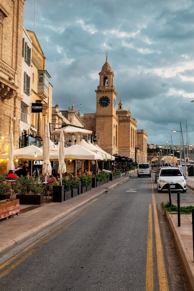 A vibrant street in Malta featuring historic architecture, cafes, and a bustling atmosphere.