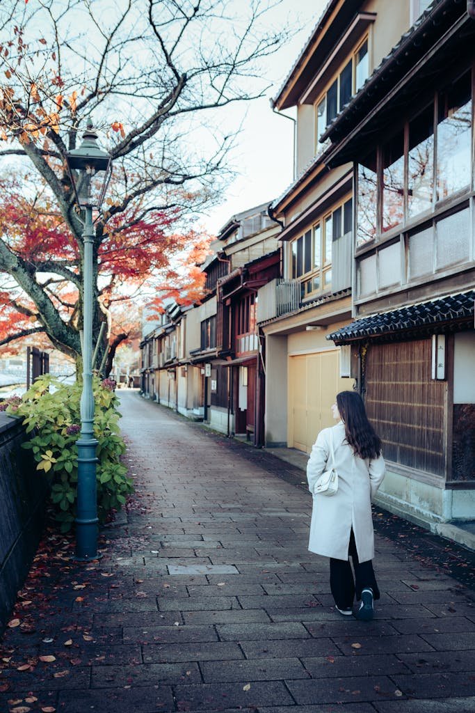 14 Best Things to Do in Kyoto, Japan + Travel Tips (2026) 5 A woman strolls down a traditional Japanese street lined with autumn foliage and classic architecture.