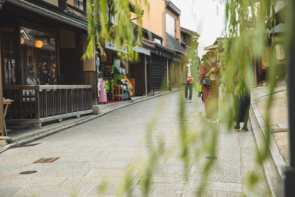 14 Best Things to Do in Kyoto, Japan + Travel Tips (2026) 16 Anonymous people in masks strolling on pavement street of city with oriental constructions