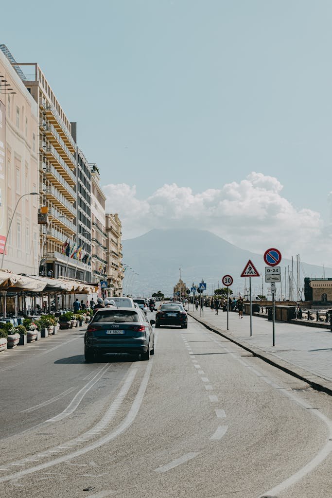 Beautiful street scene in Naples, Italy with Mount Vesuvius in the background and bustling city life.