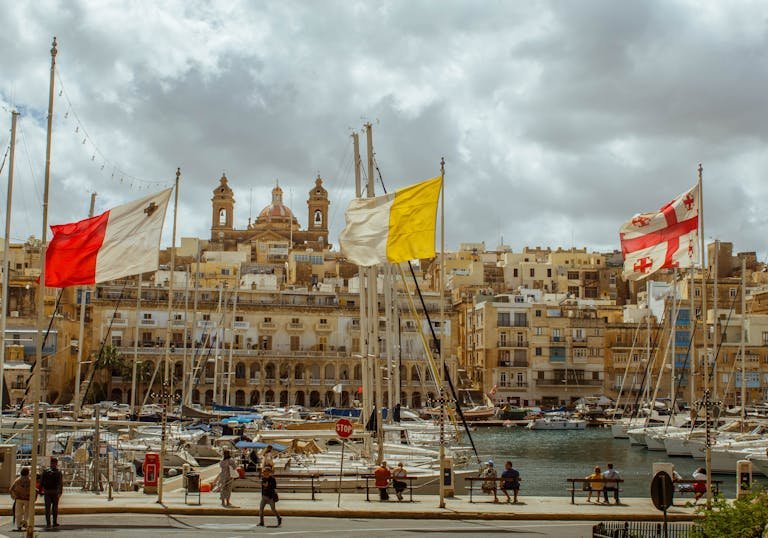 Beautiful view of a harbor in Malta with colorful flags and boats, capturing the architectural charm and vibrant atmosphere.