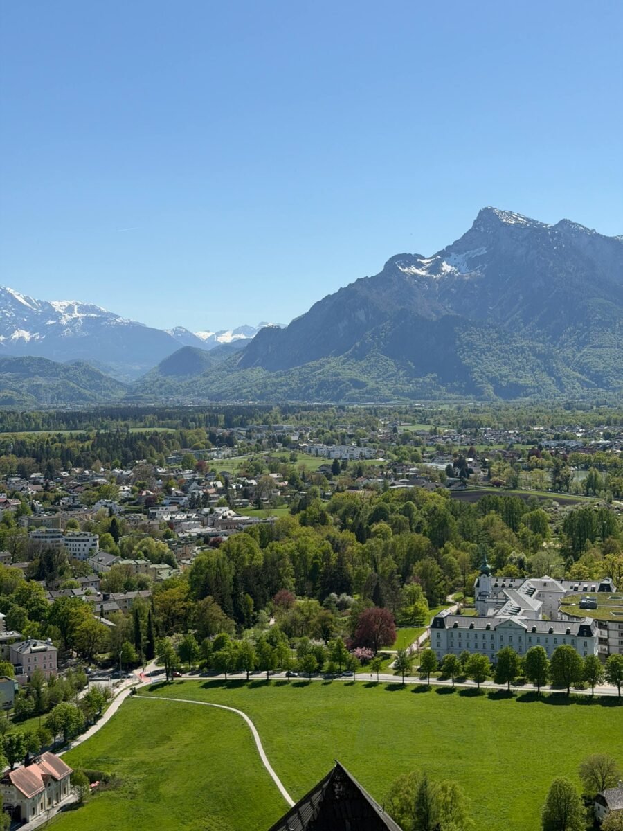 Home 21 Breathtaking aerial view of Salzburg with lush greenery and the majestic Alps in springtime.