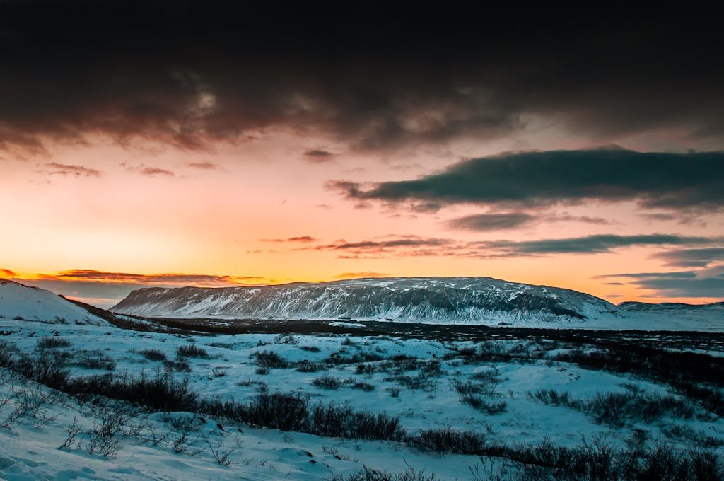 Breathtaking sunset over snowy Icelandic landscapes with dramatic clouds.