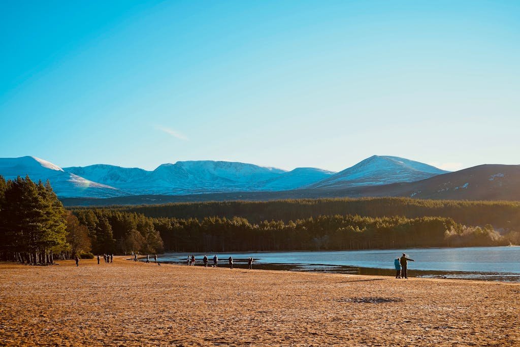Breathtaking view of Aviemore, Scotland with mountains and lake under a blue sky.