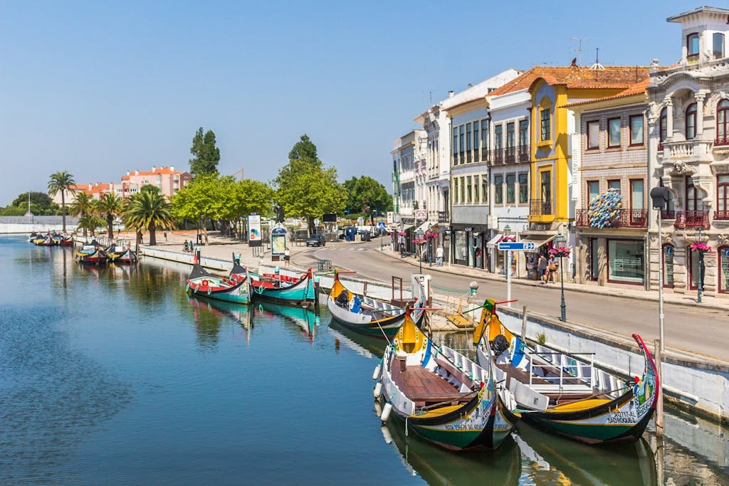Colorful gondolas along the picturesque canal in Aveiro, Portugal, under a bright sky.