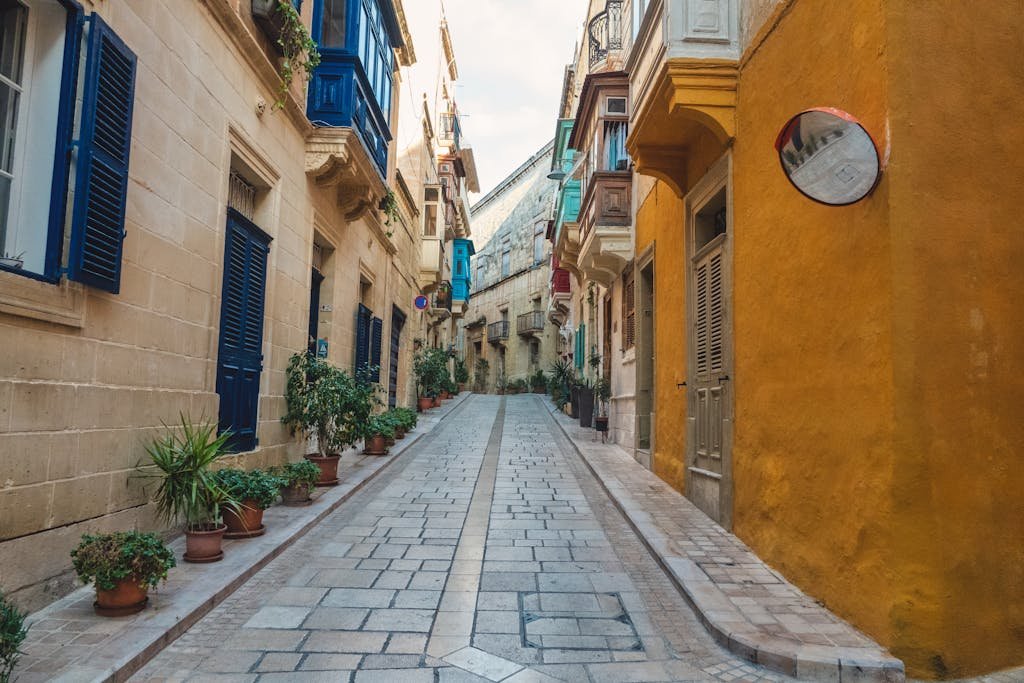 Discover a charming street in Malta featuring colorful traditional balconies and vibrant architecture.