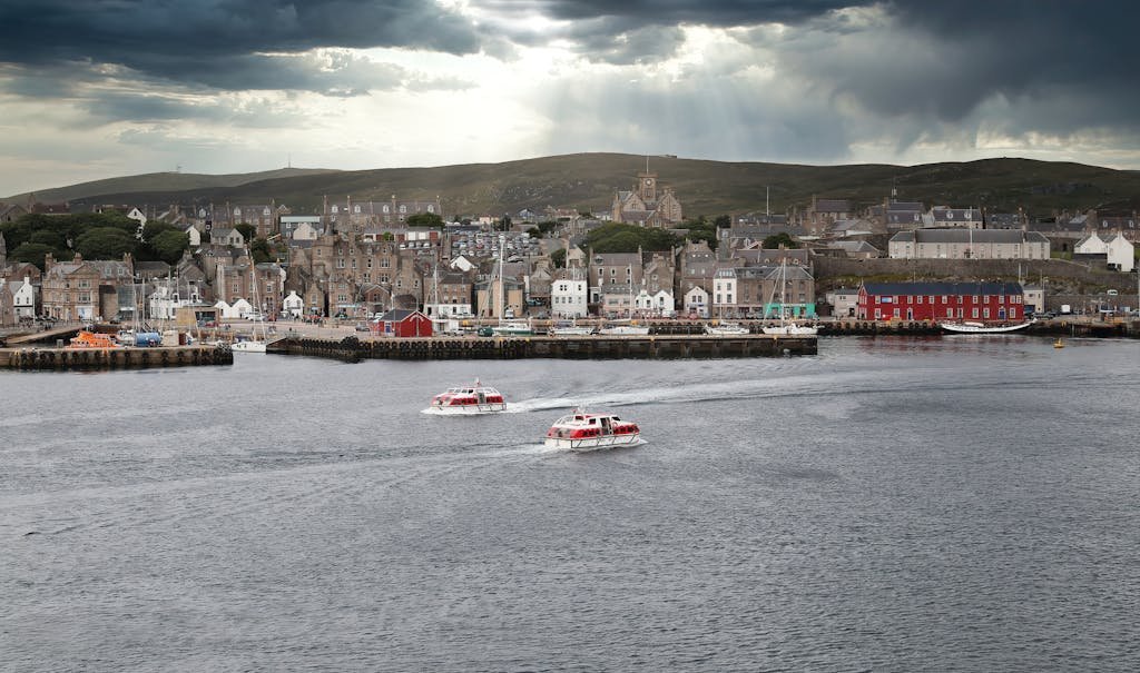 Discover Lerwick's charming waterfront with boats cruising through the scenic Scottish harbor.