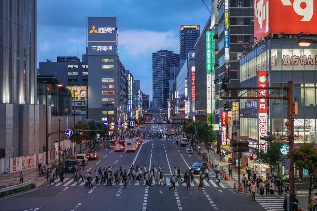 Dynamic cityscape of a vibrant street in Japan during dusk, showcasing urban life and modern architecture.