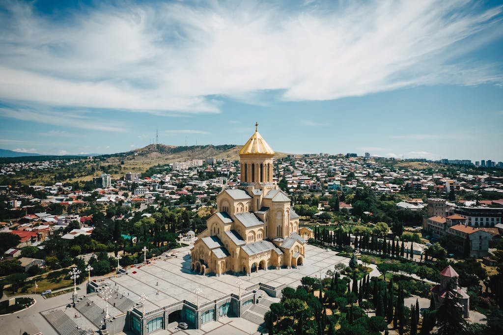 Explore the majestic Sameba Cathedral in Tbilisi from an aerial perspective, surrounded by scenic cityscape.