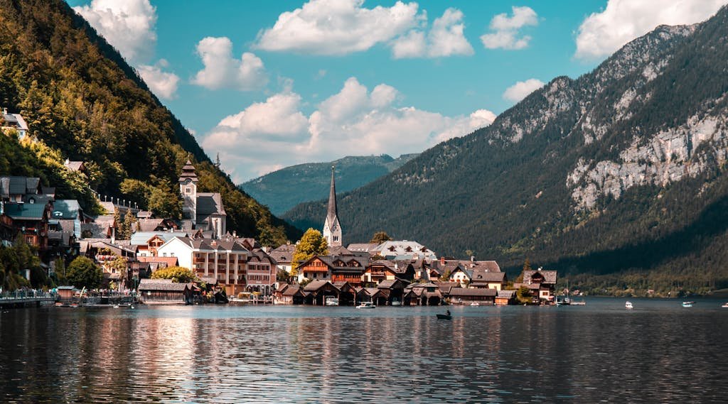 Explore the picturesque town of Hallstatt nestled by a tranquil lake, surrounded by vibrant summer landscapes and majestic mountains.