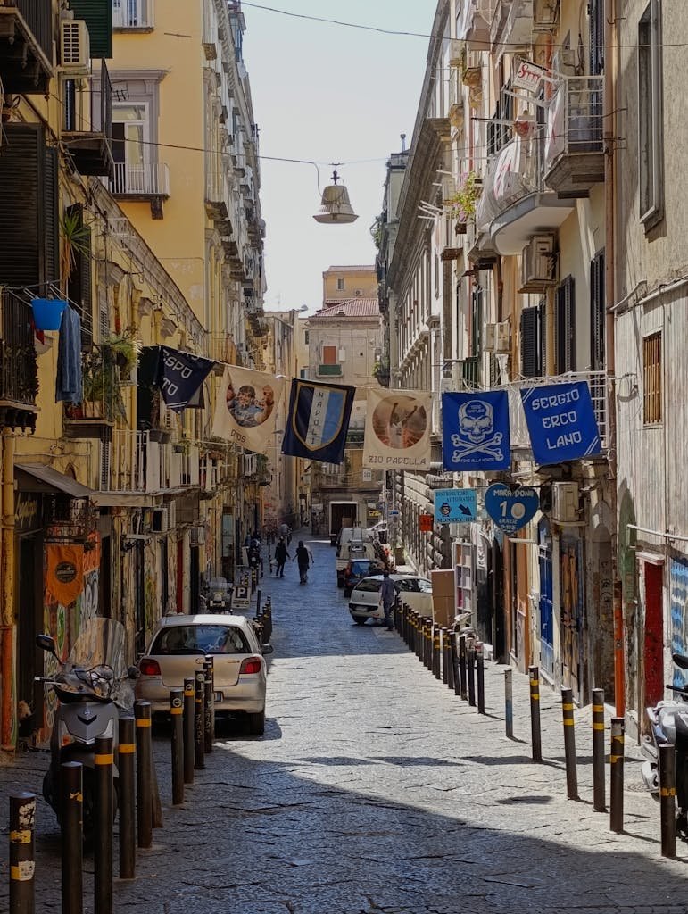 Is Naples Worth Visiting? 15 Pros and 5 Cons 3 Quaint cobblestone street in Naples with hanging banners and local architecture.