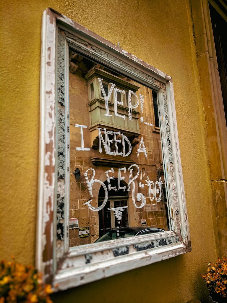 Is Malta Expensive? My Malta Budget Breakdown 2026 7 Reflective mirror with humorous text in Valletta's historic street, capturing local vibe.