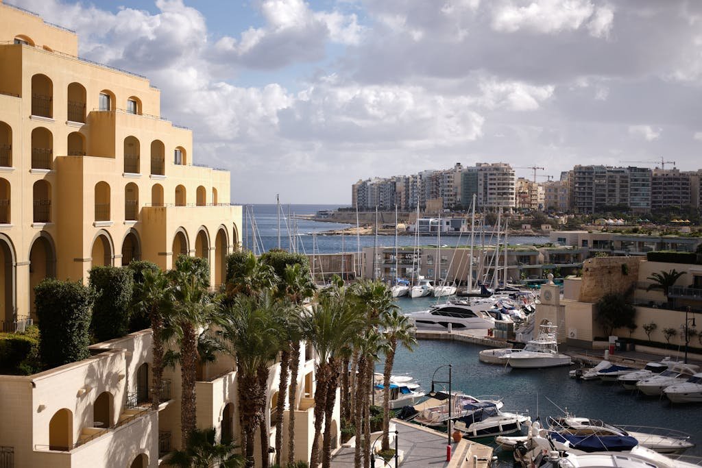 Scenic view of Hilton Malta's marina with yachts and palm trees, capturing urban luxury by the sea answers yes to is Malta worth visiting?