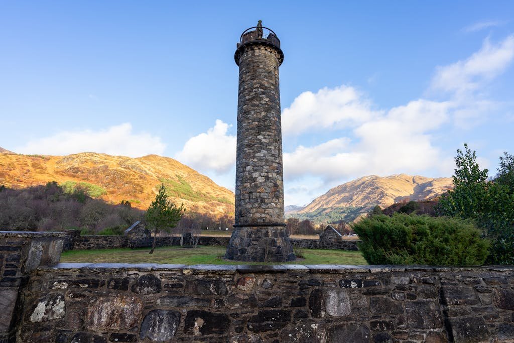 7 Day Scotland Road Trip Itinerary for First Timers 29 Scenic view of the Glenfinnan Monument surrounded by Scottish Highlands mountains under a clear sky.